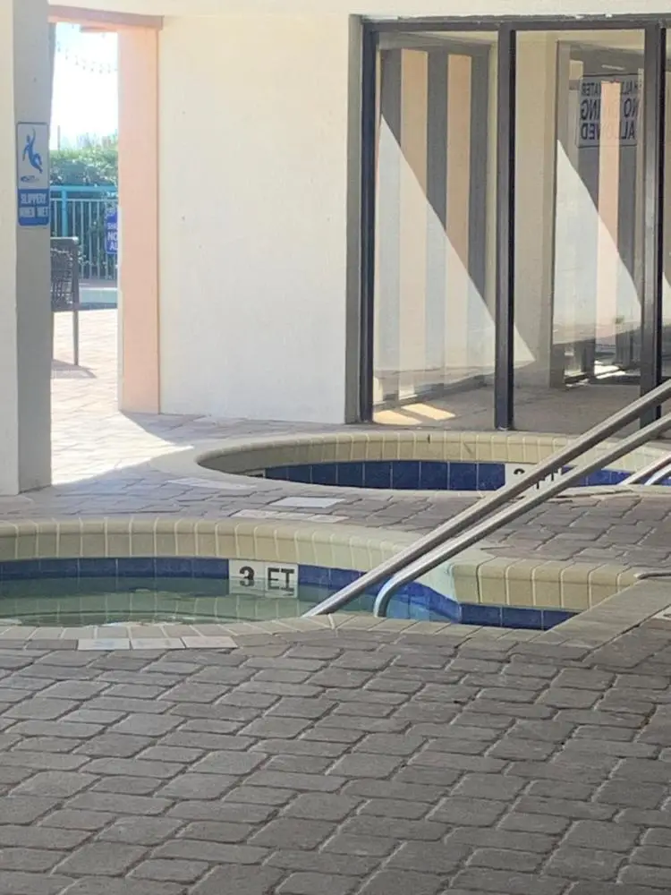 A hot tub and pool area with a tiled floor and a building in the background.